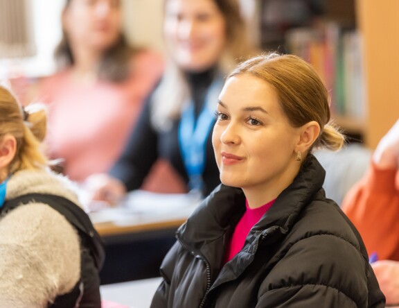 A student in a classroom, looking towards the front.