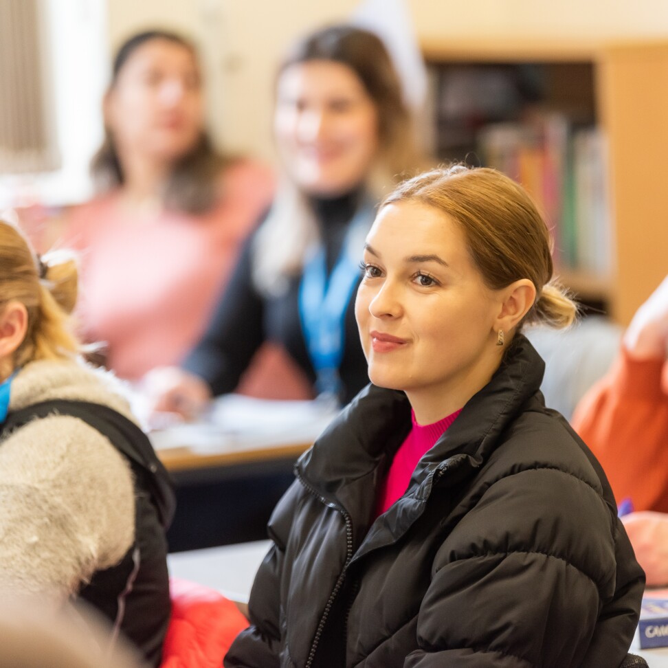 A student in a classroom, looking towards the front.