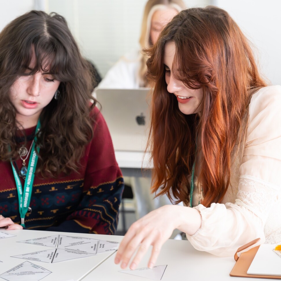 Two Childhood and Youth Studies students are sat at a table, working on a card sorting exercise.