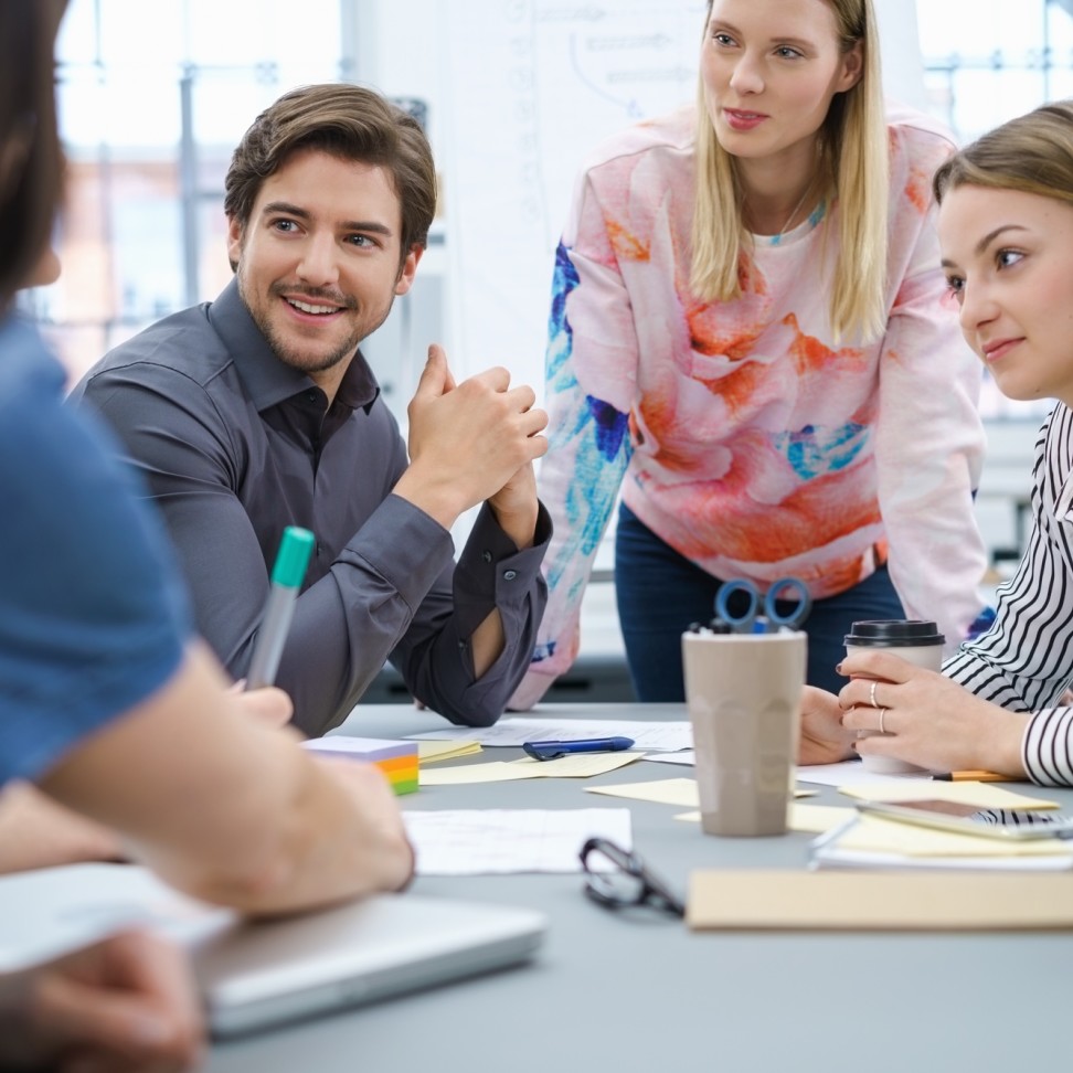 Five Chartered Manager Degree Apprenticeship students, grouped around a table in discussion.