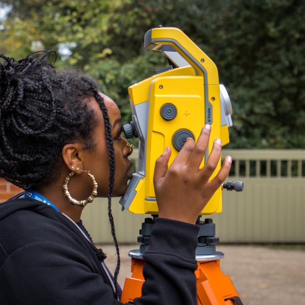 A HNC Construction Management (Construction Site Supervisor) student is looking through a surveying device.