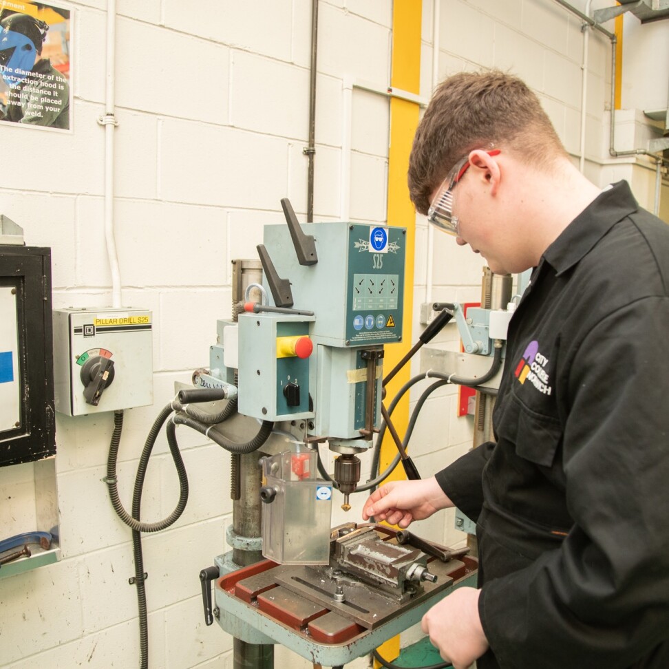 A Higher Apprenticeship Engineering Manufacturing Technician (Mechanical) student is in the workshop, using a drill machine.