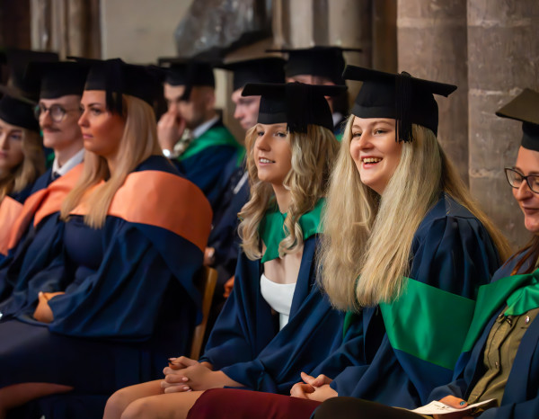Students are sat at the graduation ceremony, watching.